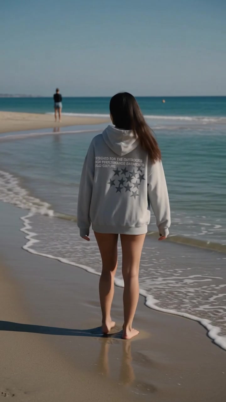 Frame from film two: the back print reading against the sea as she walks up the beach at the waterline